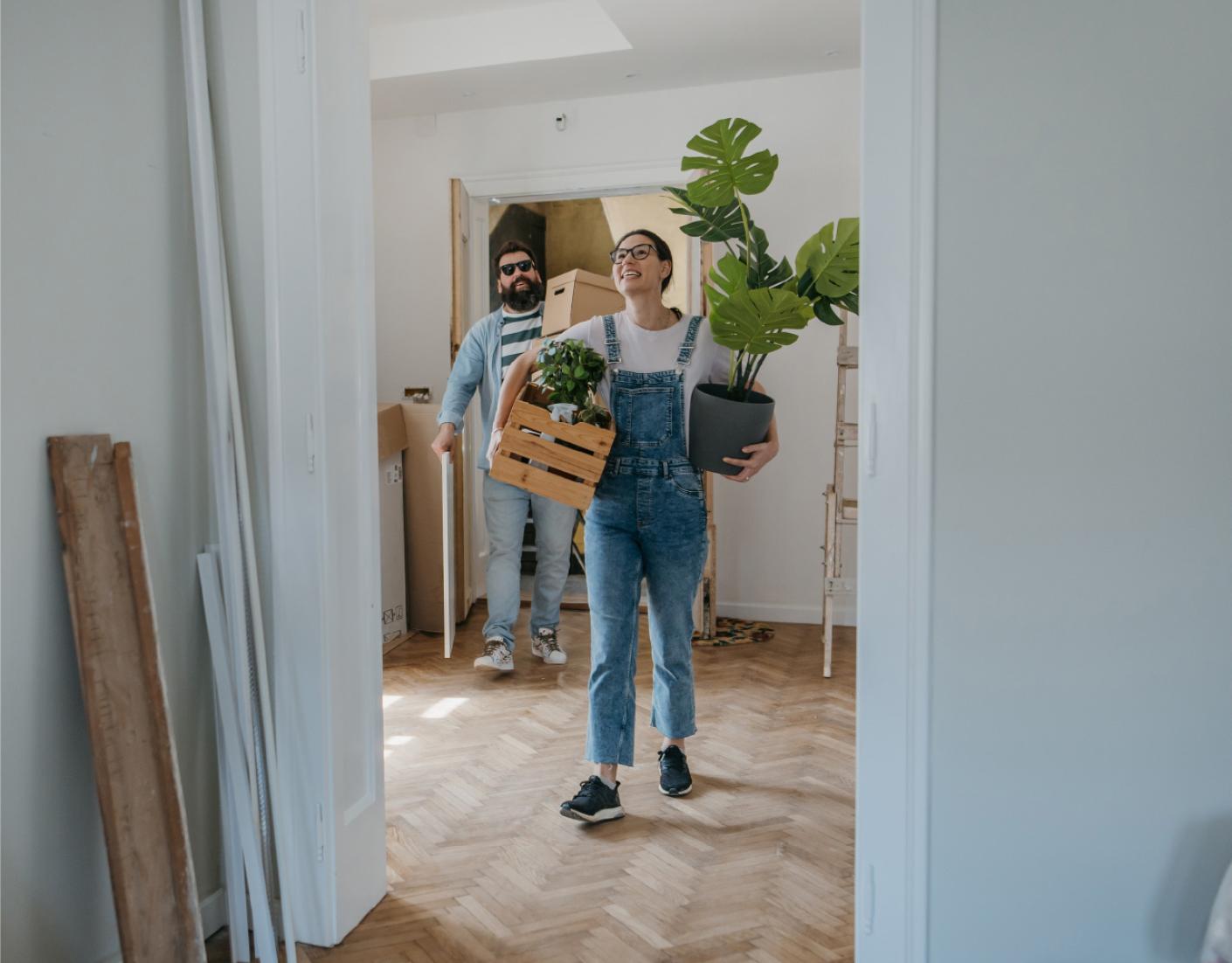 Woman and man moving boxes into a home