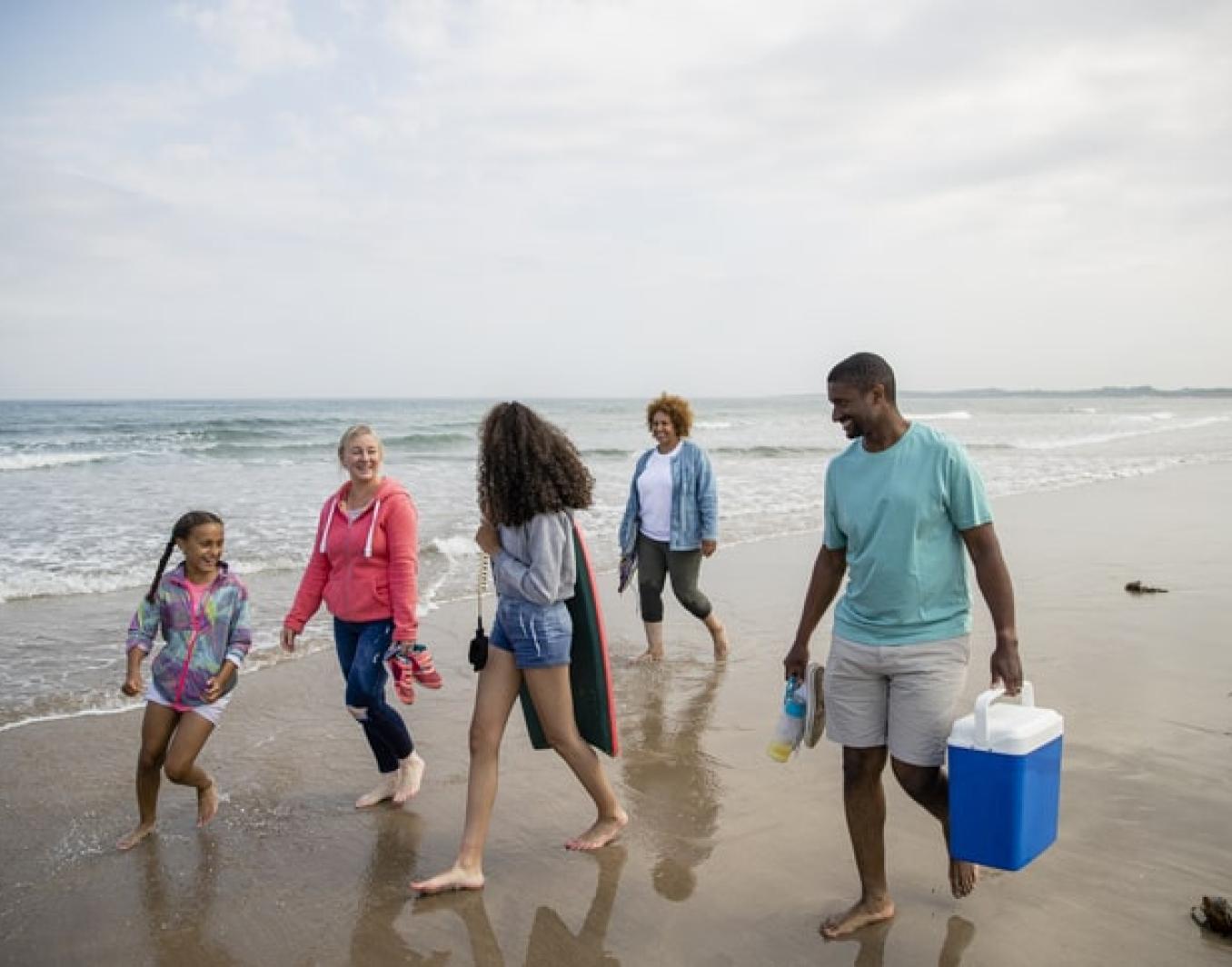 Adults and children walking on a beach.